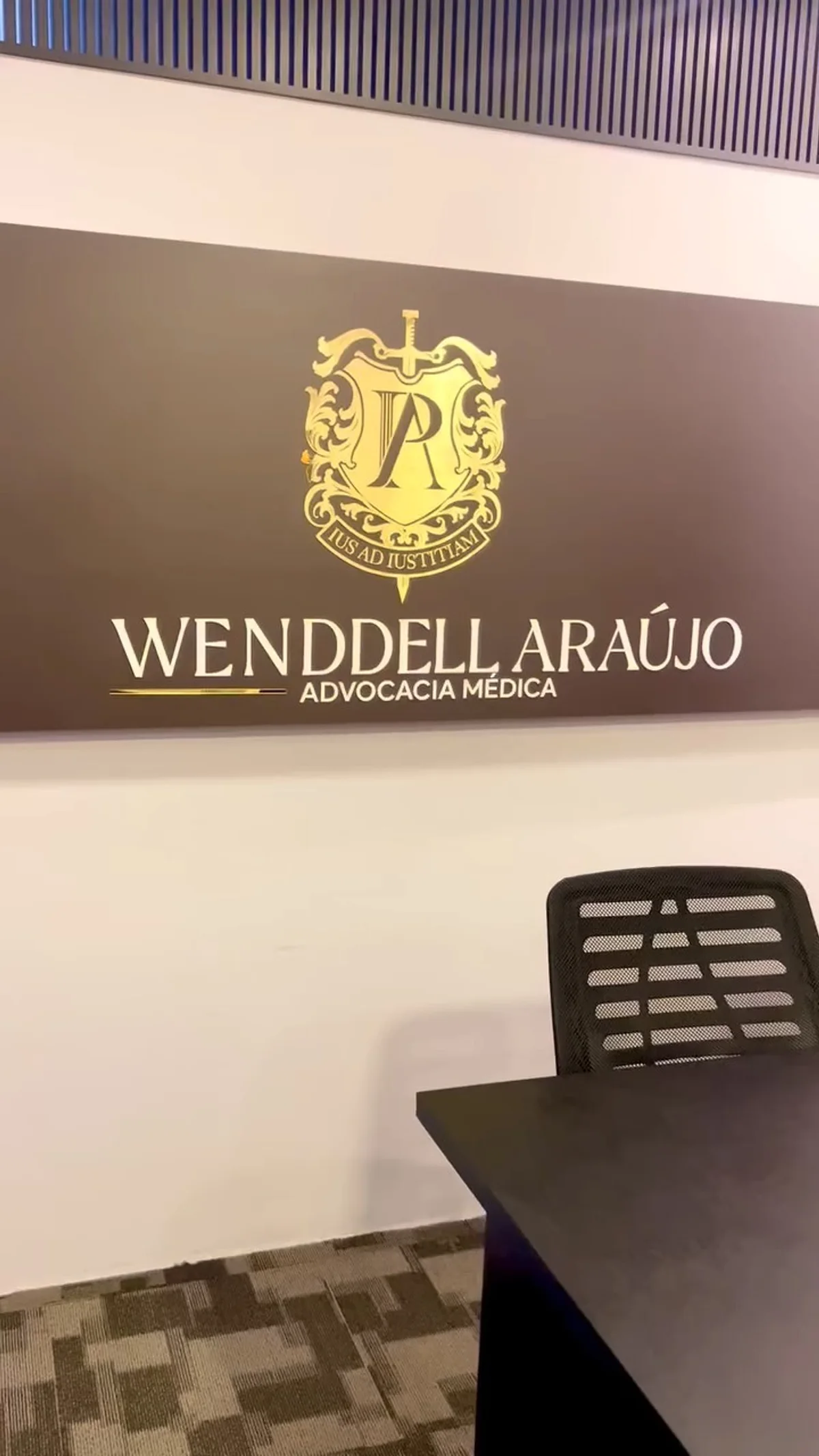 A parede da sala 715 com a placa preta e o brasão dourado: Wenddell Araújo, Advocacia Médica