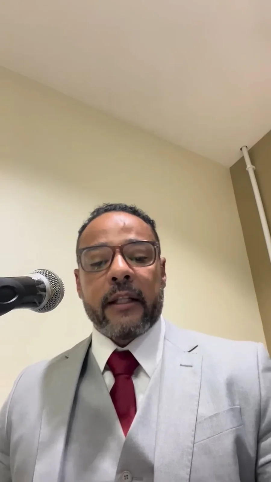 Wenddell Araújo, de terno claro e gravata vinho, falando ao microfone, visto de baixo para cima